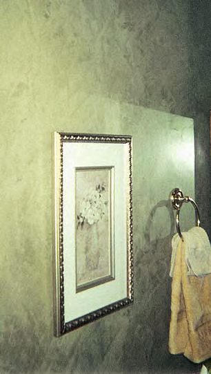 A green faux painted wall with a picture hanging on it in a bathroom.