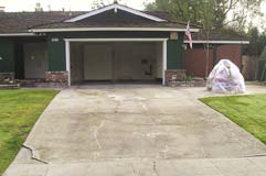 A drab concrete driveway that is in desperate need of a decorative concrete makeover.