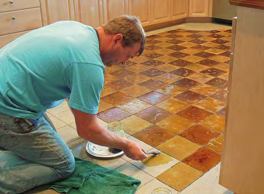 A man puts down concrete stain on a floor with a geometric pattern.