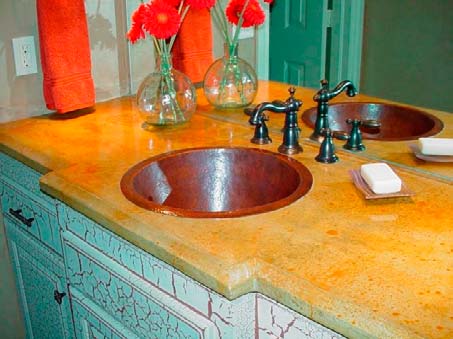 Round copper sink in bathroom concrete countertop with iron colored fixtures crackle finish cabinetry. 