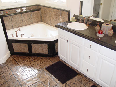 Large master bathroom with concrete countertops and a brown antiqued stamped concrete floor.