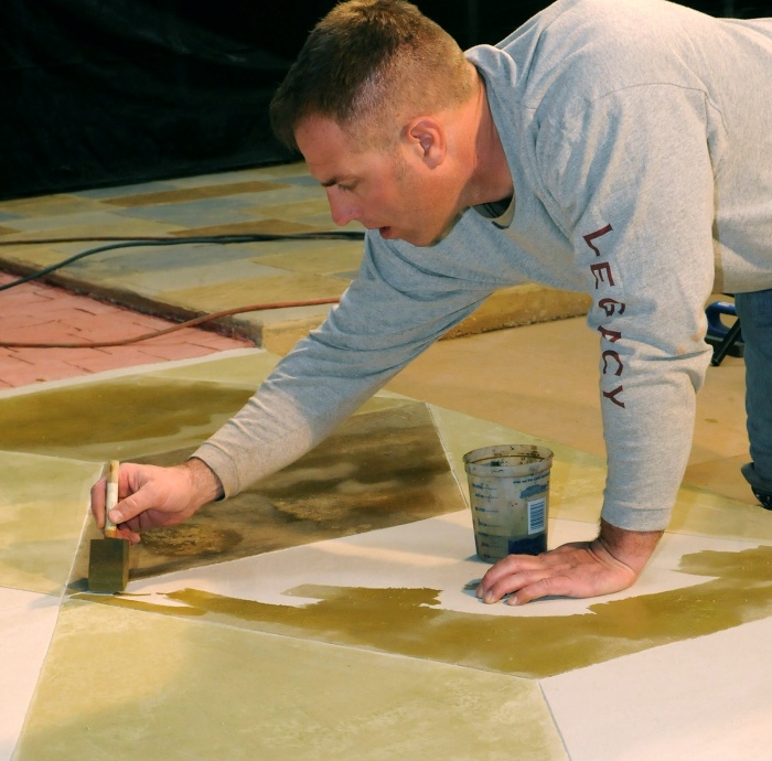 applying water-based stains to a concrete floor using a foam brush