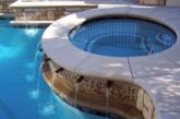 Hot tub next to a pool and a water feature keeps the water circulating.