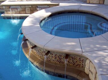 Hot tub next to a pool and a water feature keeps the water circulating.