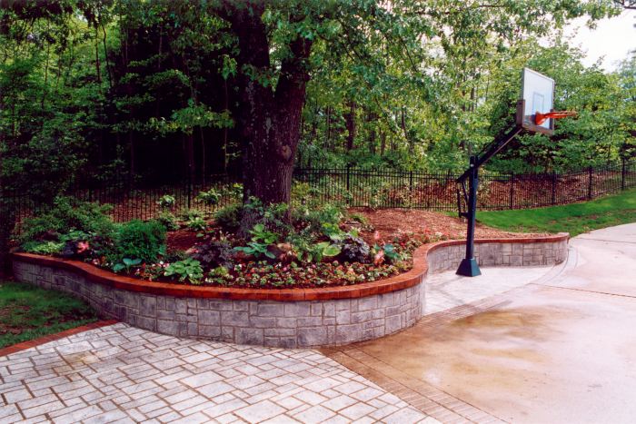 A basketball hoop and a sitting wall that acts as a planter and a retaining wall all in one.