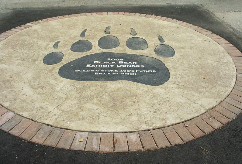 Large stamped concrete circle with a logo in the center of a bear paw.