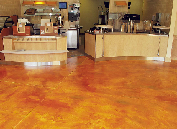 Construction materials placed on this concrete floor when it was fresh affected hydration and left circles and lines that only showed up when acid stain was applied. To solve the problem, artisans covered the ruined floor with a microtopping, then applied amber-colored acid stain to get the look originally intended.