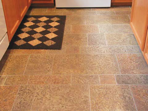 Overlay treatment in this kitchen with reds and browns and gray grout-like lines.