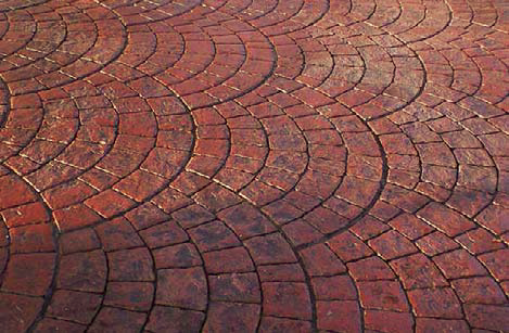Radial stamped concrete colored with a brick red.