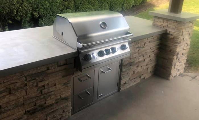 Outdoor kitchen with concrete countertop and a bbq.