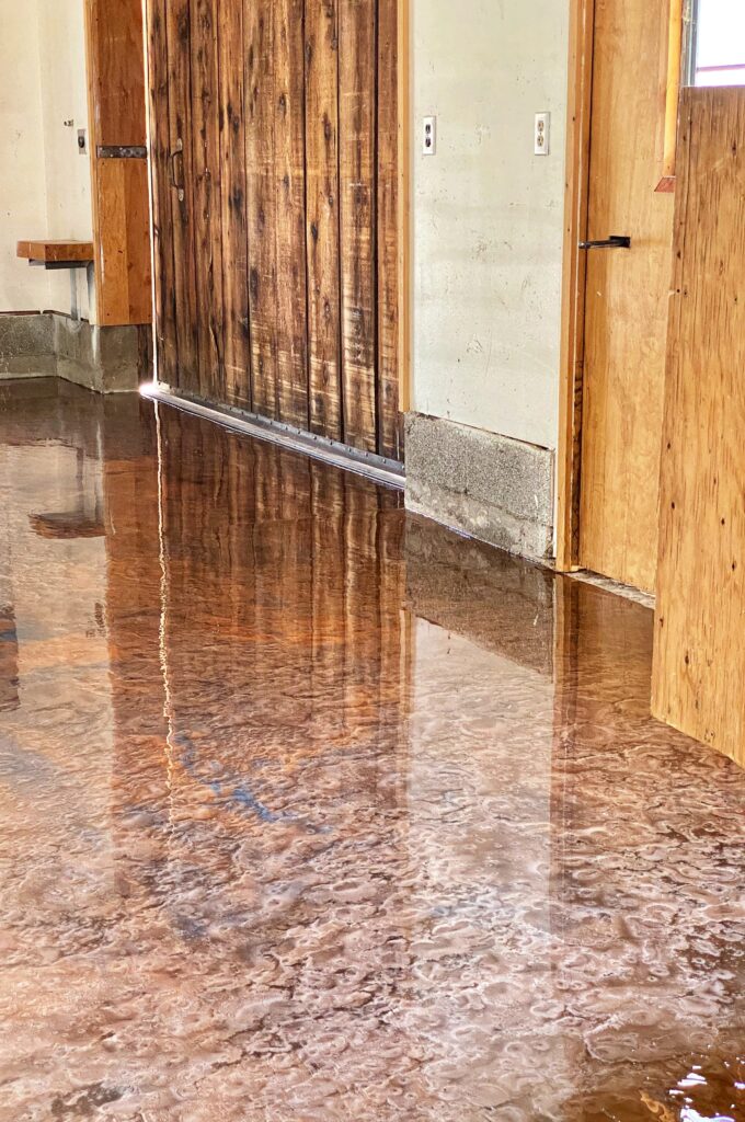 This metallic epoxy floor has a charred wood look that matches the barnwood on the exterior.