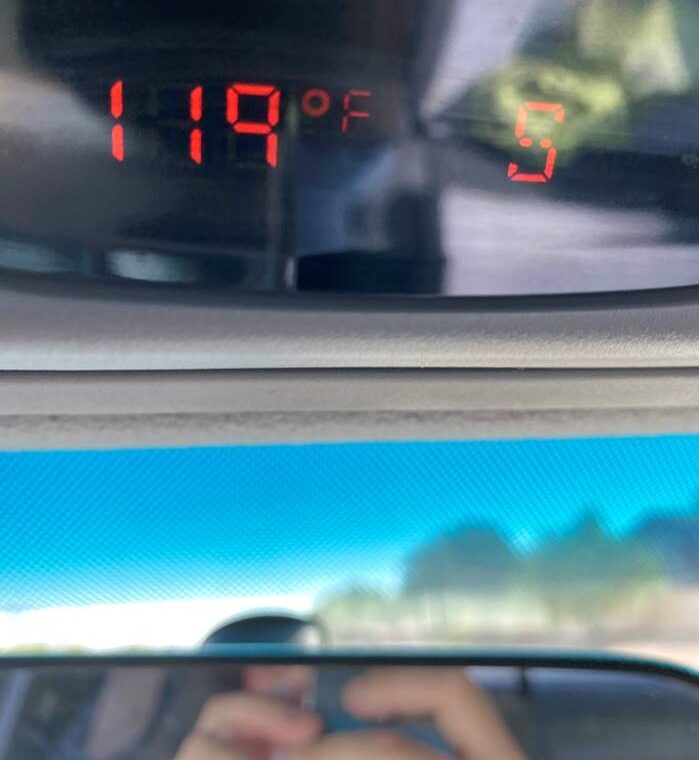 A rearview mirror reading a temperature of 119 degrees F
