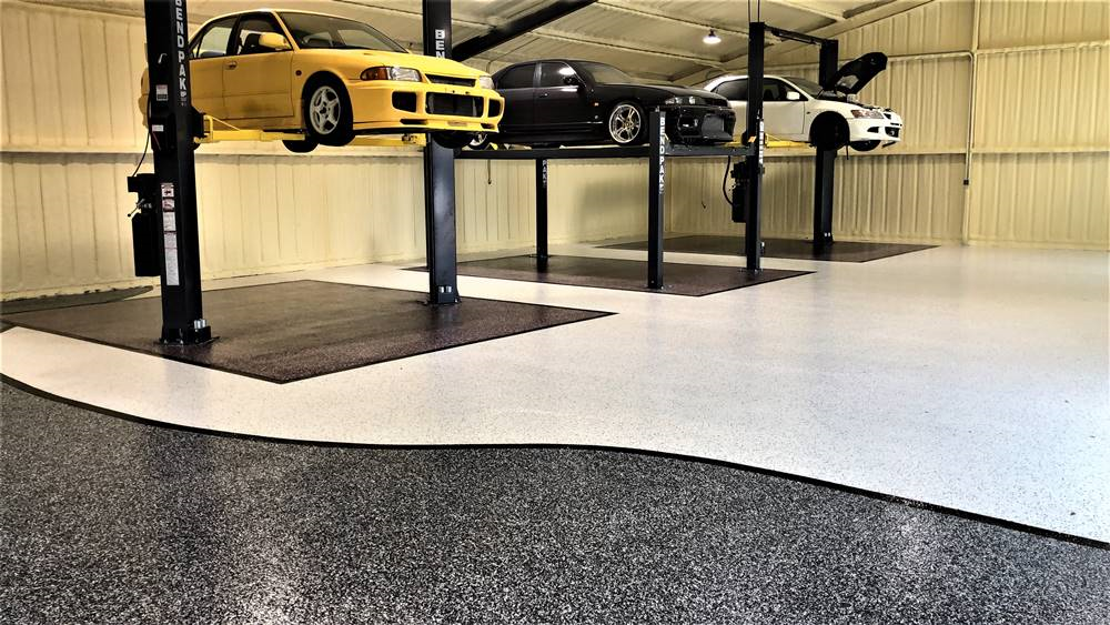 durable resinous garage floor created with Laticrete products three cars on lifts show the clean lines in black a white