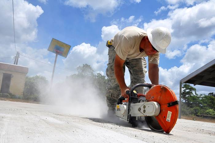A person grinding concrete without the proper PPE