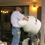 A man pours a bag mix for concrete countertops into a mixer before starting to form his countertops.