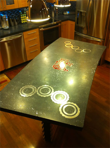 A concrete countertop that is embedded with gears and other aggregate.