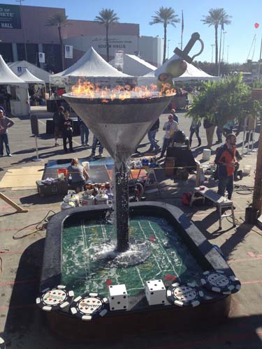 A view of the entire concrete sculpture. A martini glass on top of a craps board. All made of concrete.