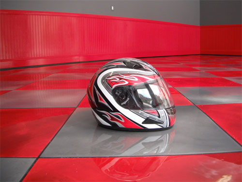 A motorcycle helmet sitting on the gray and red epoxy garage floor.