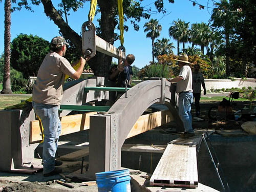 Placing the pieces of the concrete bridge using a crane and hoists.