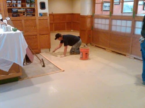 Placing the first coat of the trowelable overlay on the concrete floor.
