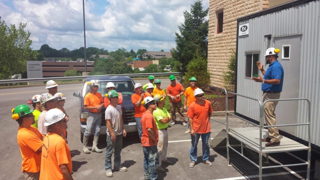 Construction workers huddle during daily safety meeting.