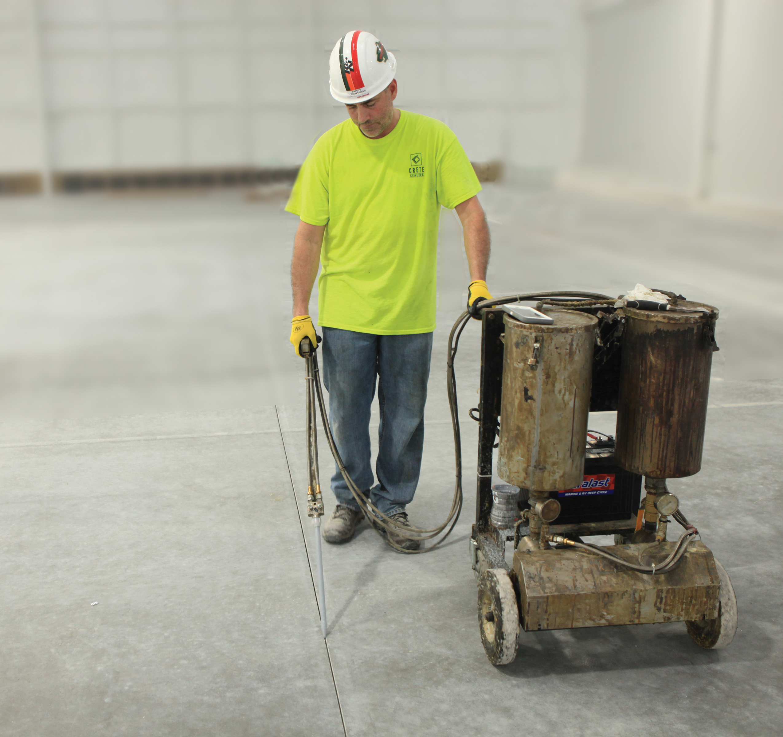 A man runs a machine that is created to fill concrete control joints.