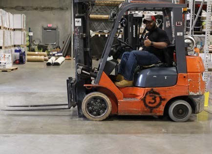 a man giving a thumbs up while sitting on a forklift