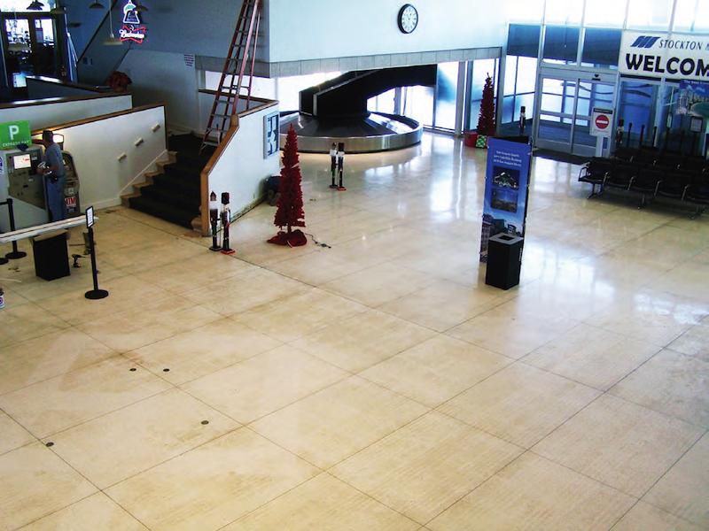 The carpet tiles were removed, revealing terrazzo floor covered in old glue, dirt and debris.