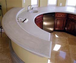 Rounded concrete kitchen countertop with a high bar top in the back in a light color.