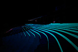 Seats at an auditorium that were painted with Glo-Kote at night when the glowing is happening.