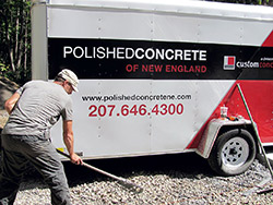 Concrete trailer with a guy spreading concrete in front of it.
