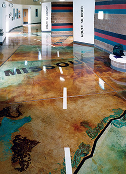 The use of a high gloss sealer over a stained concrete floor that has been designed after a large scale map.