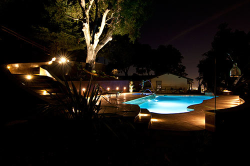 At night, this concrete pool deck is lit with well-placed lights and looks like a peaceful space.