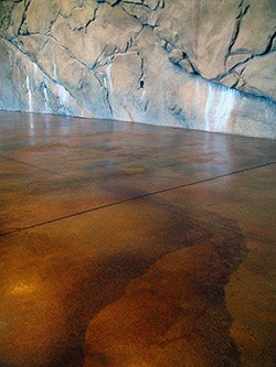 The finished garage floor in Martinez, Calif. Variegated patina stains, spotted with Ironite and graced with strata-graphics, were coordinated with the sculpted concrete rock walls.