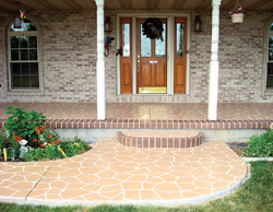 A stamped concrete entryway to a home with steps that are lined with brick-like stamp.