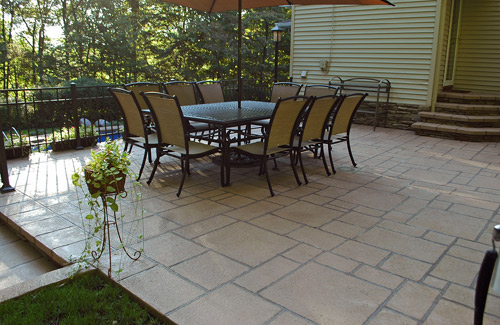 A stamped concrete patio with patio furniture.