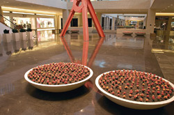 Large concrete pots surrounded by polished concrete floors with a red sculpture protruding from the floor.