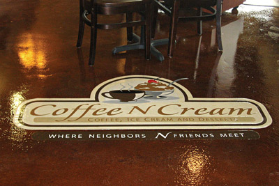 Coffee and cream logo in a stained and sealed concrete floor at a busy coffee shop.