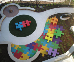 Puzzle pieces in a large scale surround a seating area in a city park.