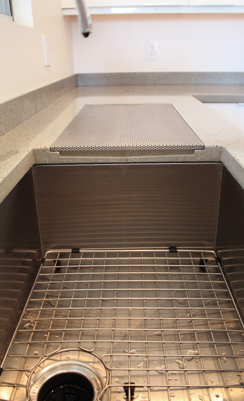 An undermount concrete sink and integrated drainboard with a removable perforated steel straining shelf. Photos courtesy of Architectural Concrete Interiors LLC