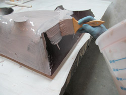 Forming concrete with fabric - After the first coats of resin are on and hardened, you can apply your Bondo-resin mix to get a sandable and workable surface.