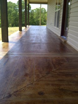 For a 10-inch border around the perimeter of the concrete porch surface, Thorn cut a grout line and applied a dark-colored acid stain outside of the grout, using a color called Black Walnut from Concrete Resurrection, an Engrave-A-Crete company.