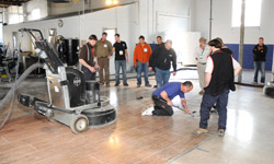 Polishing machine sits on the concrete slab while attendees look on.