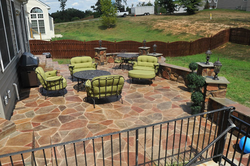 Circular stamped concrete backyard patio enhances the lime green cushioned iron patio furniture.