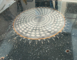The coolest polished concrete floor ever, looks like a metal saw blade has been placed in a dark gray dyed concrete floor with lighter color dot circular pattern radiating out from the center. 