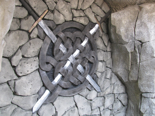 A celtic knot with swords carved onto the wall in concrete.