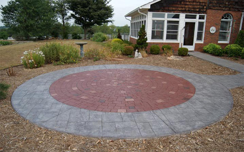 A radial stamped patio that is gray and red and looks like pavers.