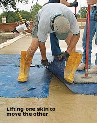 Lifting Concrete Skins while moving another skin next to it. Man in yellow boots leaning over manipulating concrete skins.
