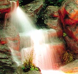 Water tumbling down a concrete rock stream being highlighted by a red glow.