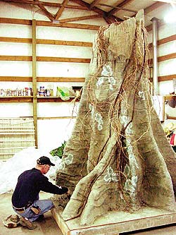 Concrete tree trunk being modified by a Lakeland employee.